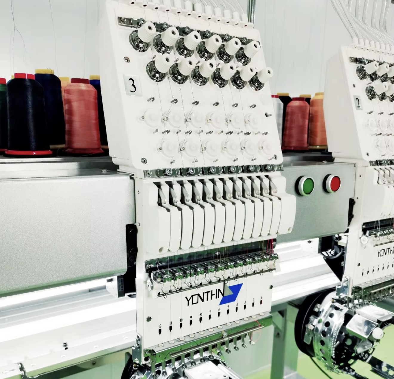 12-Nadel-Stickkopf einer SABOTAGE-Produktionsmaschine, Garnrollen im Hintergrund
